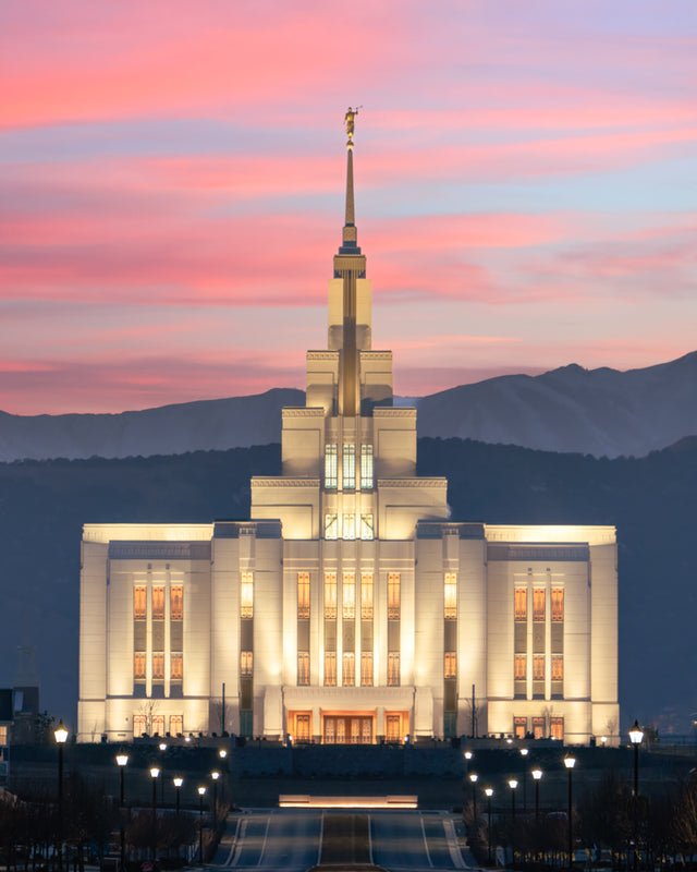 The Saratoga Springs Utah temple in the evening with pink clouds and mountains.