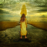 A young woman stands on a ledge looking toward the sails of a ship.