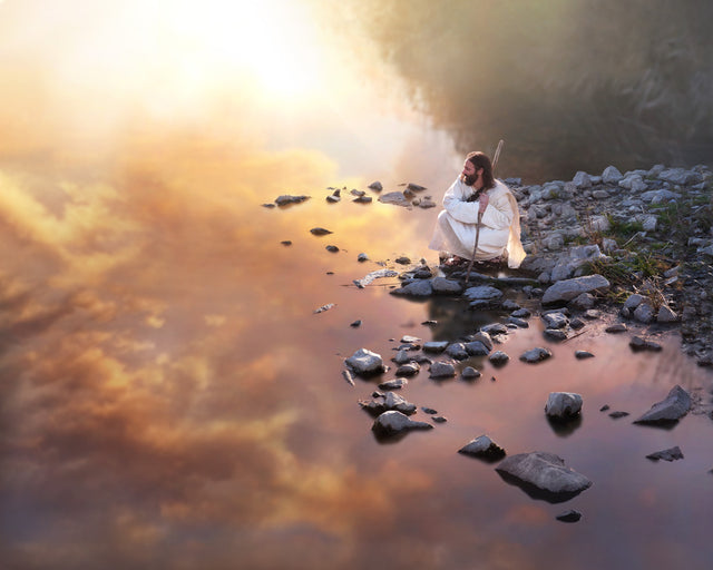 Jesus kneeling at edge of water in contemplation. 