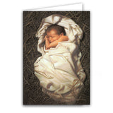 A peaceful baby sleeping in a straw-filled manger, beautifully depicted for a Boxed Christmas Card design.